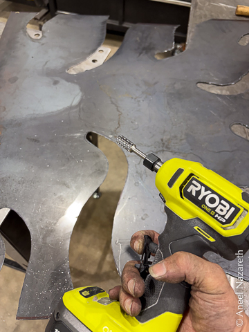 A pistol grip die grinder is held in a filthy hand